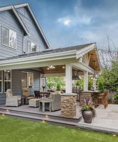 an outdoor living area with patio furniture and grass in front of a blue house on a sunny day