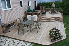 a wooden deck with chairs and tables next to a house