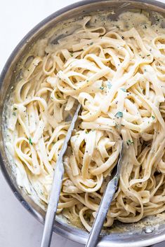 a bowl filled with pasta and two silver spoons