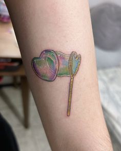 a colorful tattoo on the leg of a person with a heart shaped umbrella and a toothpick