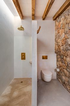 a bathroom with stone walls and flooring next to a white toilet in the corner