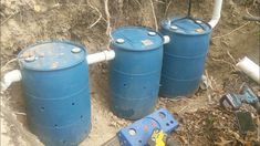 three blue barrels sitting next to each other on the ground near some pipes and tools