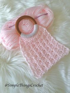 a crocheted pink hat, scarf and wooden ring on white furnishing