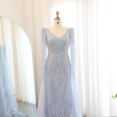 Make a statement in this luxurious Dreamy Vow Mermaid Light Blue Evening Dress with flowing cape sleeves. Elegant and flattering, this plus size gown is perfect for any wedding guest or party. You'll feel like royalty in this stunning piece. Luxury Sequined Dresses With Cape Sleeves, Blue Evening Dress With Cape Sleeves, Elegant Blue Maxi Dress With Cape Sleeves, Blue Embellished Dress With Cape Sleeves, Luxury Light Blue V-neck Maxi Dress, Yellow Evening Dresses, Grey Evening Dresses, Champagne Evening Dress, Gold Evening Dresses