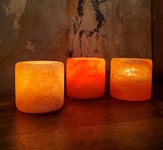 three square candles sitting on top of a wooden table