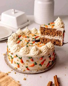 a carrot cake with white frosting on a plate next to a slice cut out