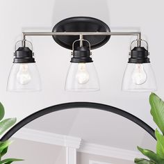 three light bathroom fixture with clear glass shades and black metal frame, hanging from the ceiling