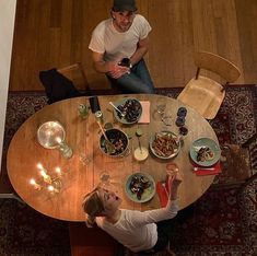 two people sitting at a table with food on it