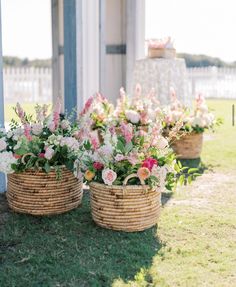 two baskets filled with flowers sitting on top of a grass covered field next to a building