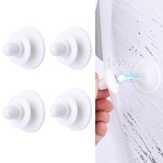 four white door knobs and one is being held by a hand