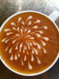 there is a cup of coffee with white designs on it