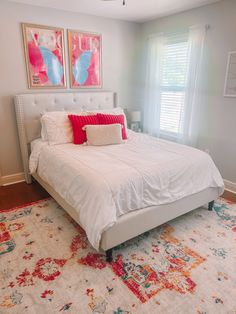 a white bed sitting in a bedroom on top of a rug next to a window