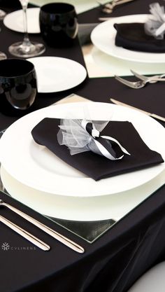 the table is set with black and white plates, silverware, and napkins