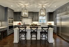 an image of a kitchen with gray cabinets and white counter tops, including the island