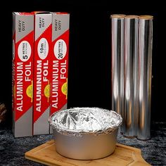 an aluminum foil covered dish sitting on top of a cutting board next to two books