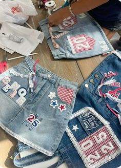 two pairs of jean shorts with patches and numbers on them, sitting on a table