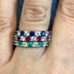 a woman's hand with three different colored stones on it and an engagement ring