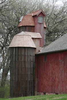 an old red barn and silo in front of trees with no leaves on them