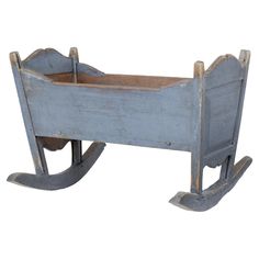 an old blue wooden rocking toy bed with no sheets on the top and bottom sides