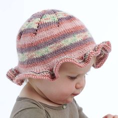 a small child wearing a knitted hat and looking down at something in her hands