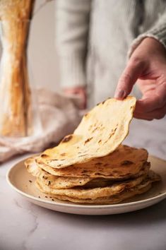 a stack of flatbreads on a plate being held by a person's hand