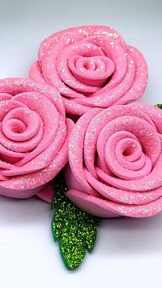 three pink roses with green glitters on them sitting next to each other in a white bowl