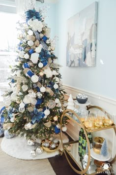 a blue and white christmas tree in a living room with gold trimmings on it