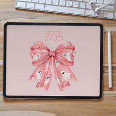 an ipad with a pink bow on it next to a keyboard and mouse, along with a cup of coffee