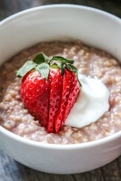 a white bowl filled with oatmeal topped with a strawberry