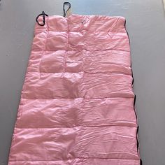 a pink sleeping bag sitting on top of a floor next to a white wall with a black handle