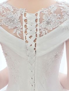 the back of a woman's wedding dress with white lace and flowers on it