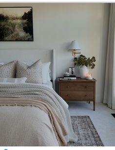 a bedroom with a bed, nightstand and painting on the wall above it that has candles in front of it