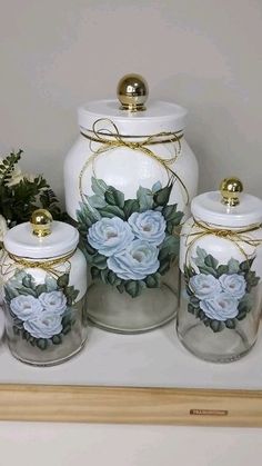 four glass jars with flowers painted on them