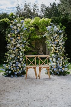 a wooden bench sitting in front of a flower covered arch with blue and white flowers