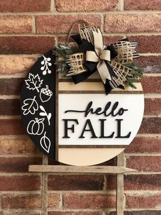 a black and white sign that says hello fall hanging on the side of a brick wall