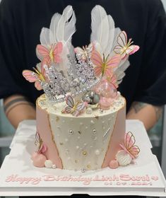 a birthday cake is decorated with pink and white flowers, butterflies, and jewels on it