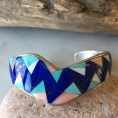 Amazing Unique Vintage Native American Navajo Bracelet. Handcrafted By Silversmith Lorraine Long. Superior Quality. Contemporary, Stylish, Geometric Design, Inlaid Deep Blue Lapis, Turquoise, Angel Coral, Jet, Triangles. A Beauty, Statement Piece Size 6 1/8” Total Inner Measurement 5 1/8” Cuff Plus A 1” Opening For The Total Size Of 6 1/8. This Bracelet Does Not Bend Weight 58.2 Grams Hallmark Lorraine Long Stamped Sterling Condition New, Never Worn, From 1980's Vintage Collection Native American Jewelry Bracelets, Blue Inlay Bracelet Jewelry, Blue Inlay Bracelet, Handmade Bohemian Blue Sterling Silver Bracelet, Artisan Blue Sterling Silver Bracelets, Artisan Blue Sterling Silver Bracelet, Traditional Blue Sterling Silver Bracelets, Southwestern Sterling Silver Cuff Bracelet In Blue, Southwestern Blue Sterling Silver Bracelet Gift