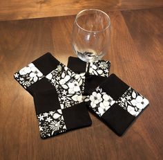 four black and white coasters with flowers on them next to a glass of wine