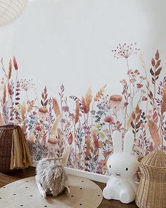 a room with flowers painted on the wall and a stuffed animal sitting in front of it