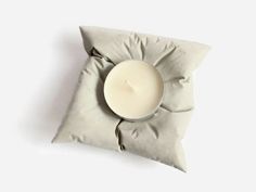 a white candle sitting on top of a pillow