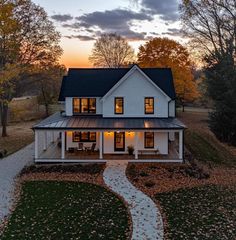 a large white house with a black roof and windows on the front porch at sunset