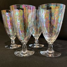 four wine glasses sitting on top of a table next to each other in front of a black background