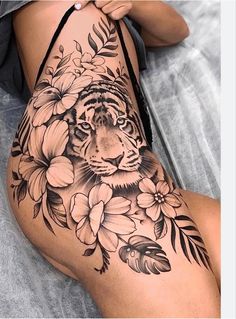 a woman's leg with a tiger and flowers tattoo on it