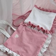 a pink and white purse sitting on top of a bed next to a bag with ruffles