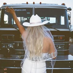 a woman in a white dress and hat standing next to a truck