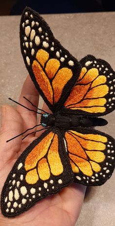 a hand holding a yellow and black butterfly