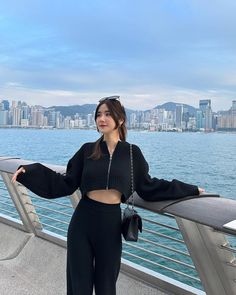 a woman is standing on a bridge near the water