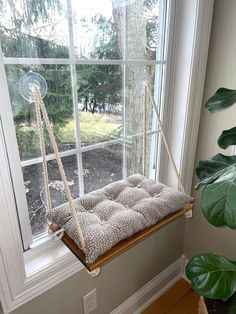 a window sill with a cushion hanging from it's side, in front of a large window