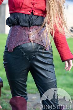 a woman with long blonde hair wearing black leather pants and red shirt standing in front of a fire hydrant