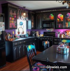 a kitchen with black cabinets and colorful decorations on the walls, along with a dining room table